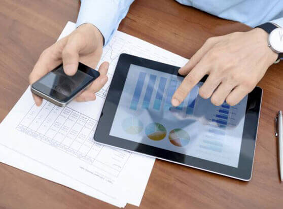 Man holding a phone while touching a tablet